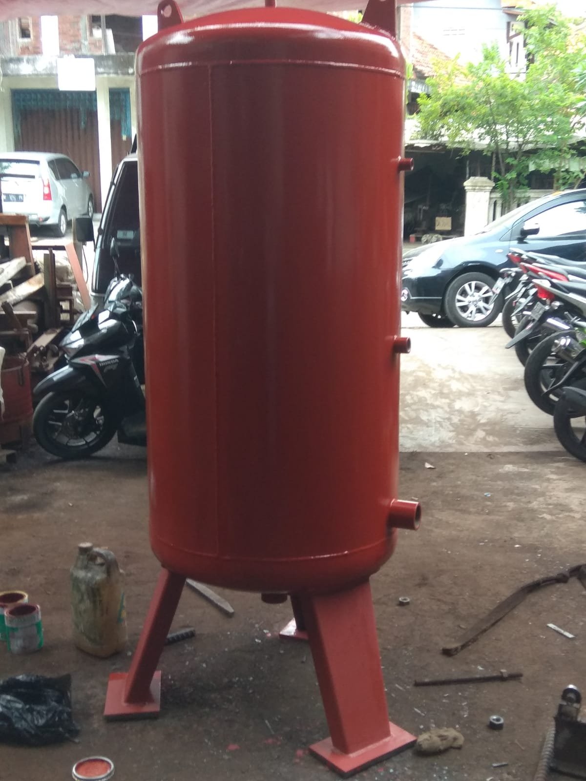 Red vertical pressure vessel with service nozzles and support legs